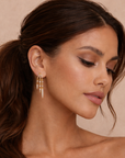 Woman wearing gold hoop earrings with a neutral background