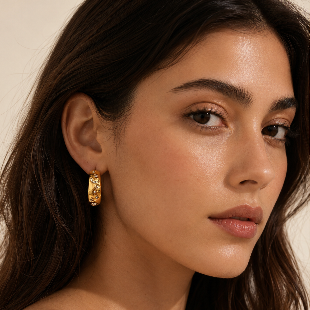 Close-up of a woman wearing gold hoop earrings with a neutral background