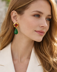 Woman wearing a pair of earrings with a blurred outdoor background