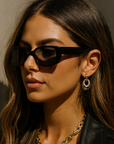 Woman wearing sunglasses and a black leather jacket against a neutral background