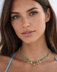 Woman wearing a blue top and a necklace with a star charm against a blurred natural background