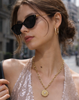 Woman wearing a sparkly top and gold necklace on a city street