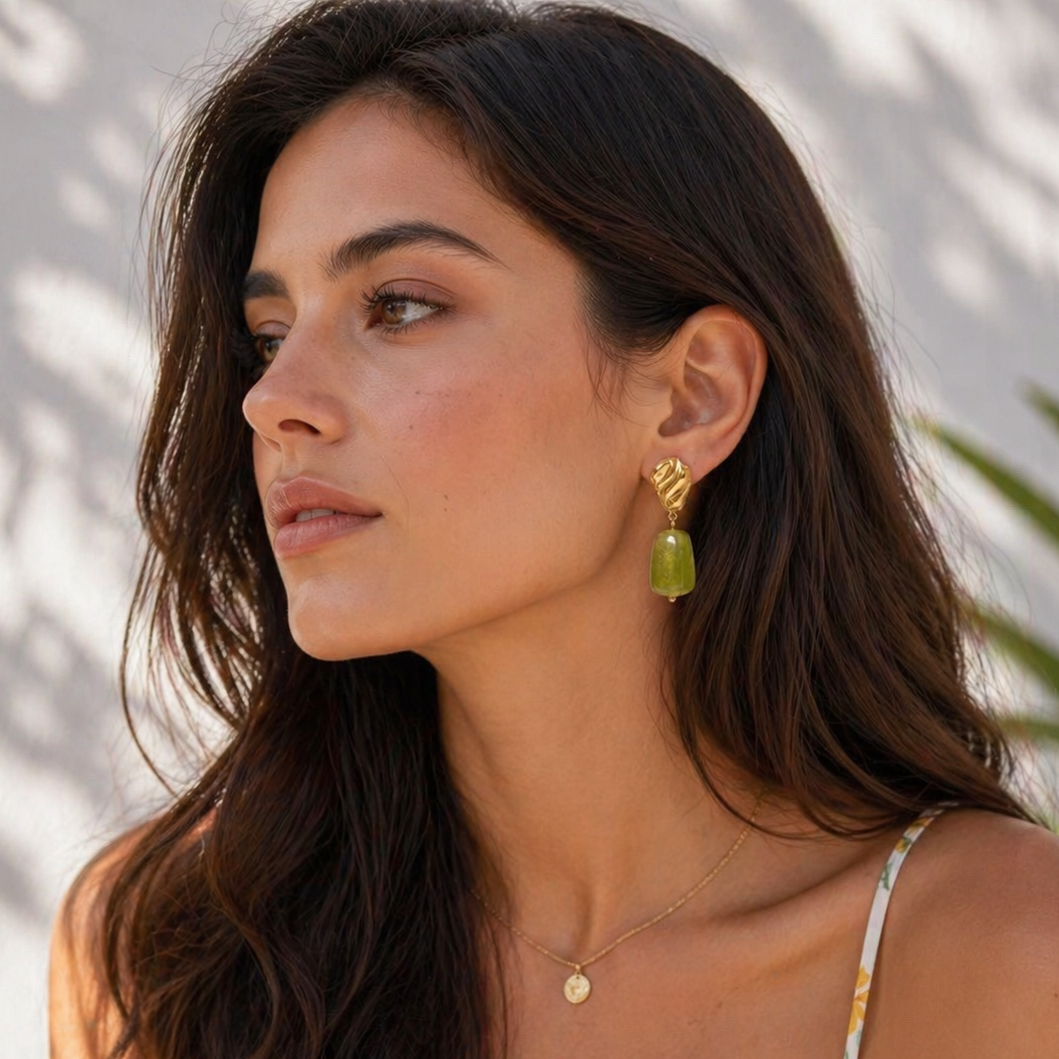 Woman wearing gold earrings and a necklace with a blurred background