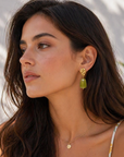 Woman wearing gold earrings and a necklace with a blurred background