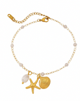 Gold anklet with starfish, shell, and pearl charm on a white background