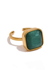 Gold ring with a green square stone on a white background