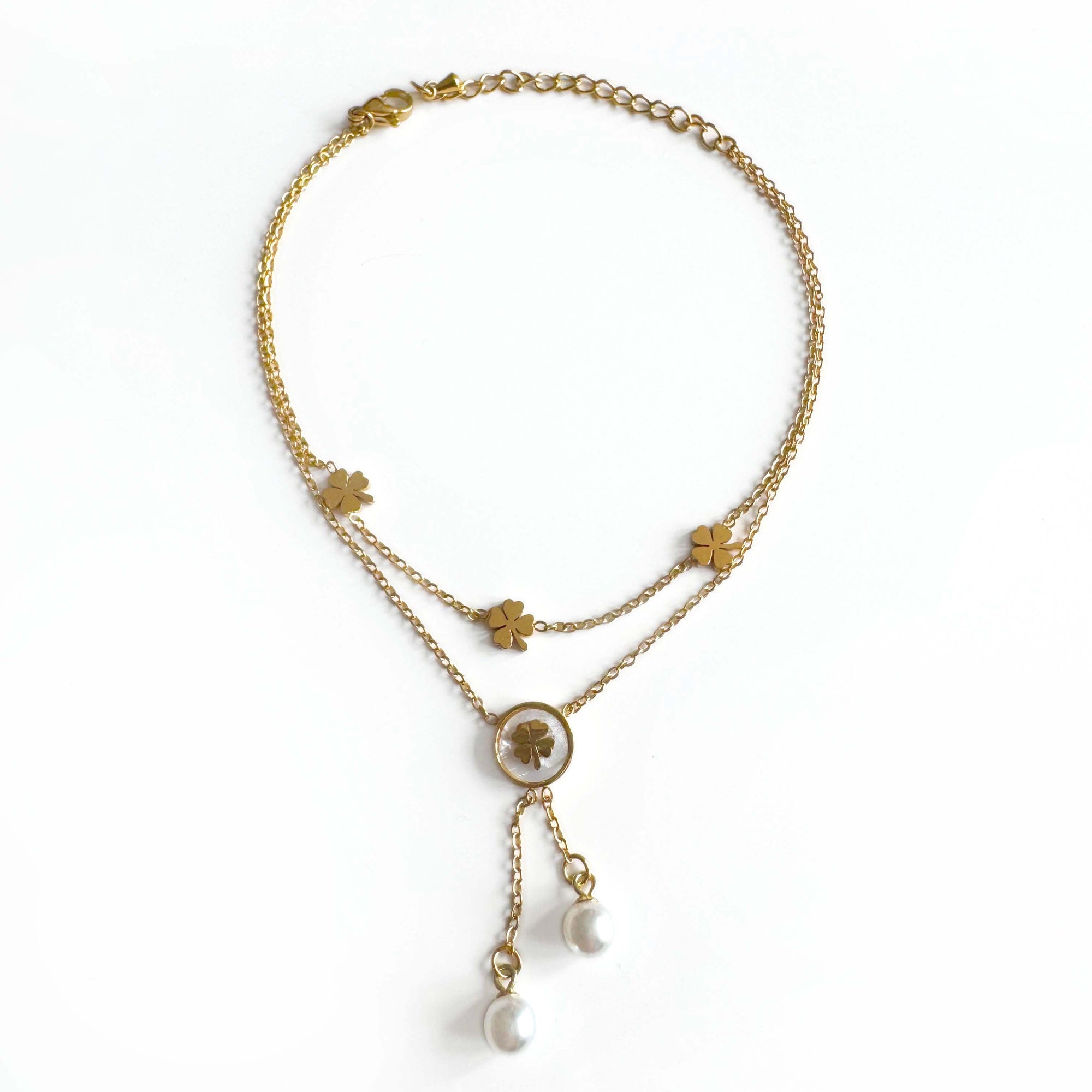 Gold anklet with four leaf clover charms on a white background