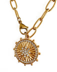 Gold necklace with a sunburst pendant on a white background